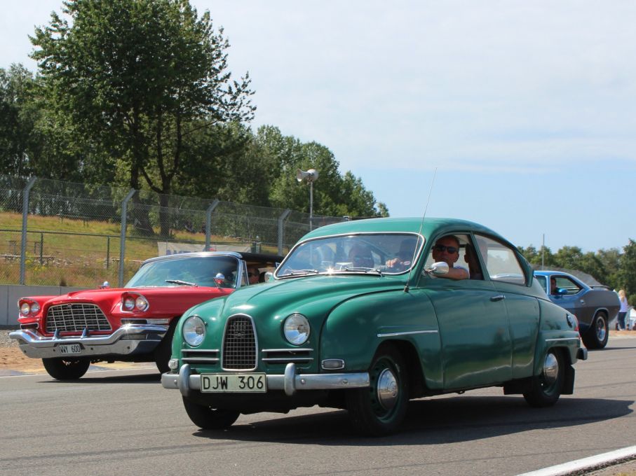 Skilda världar. Svensk trubbnos defilerar med samtidens värsting, Chrysler 300D. Den hade en V8 på 6,5 liter och 380 hästar, i motsats till Saabens modesta 750cc och 33 hästkrafter.